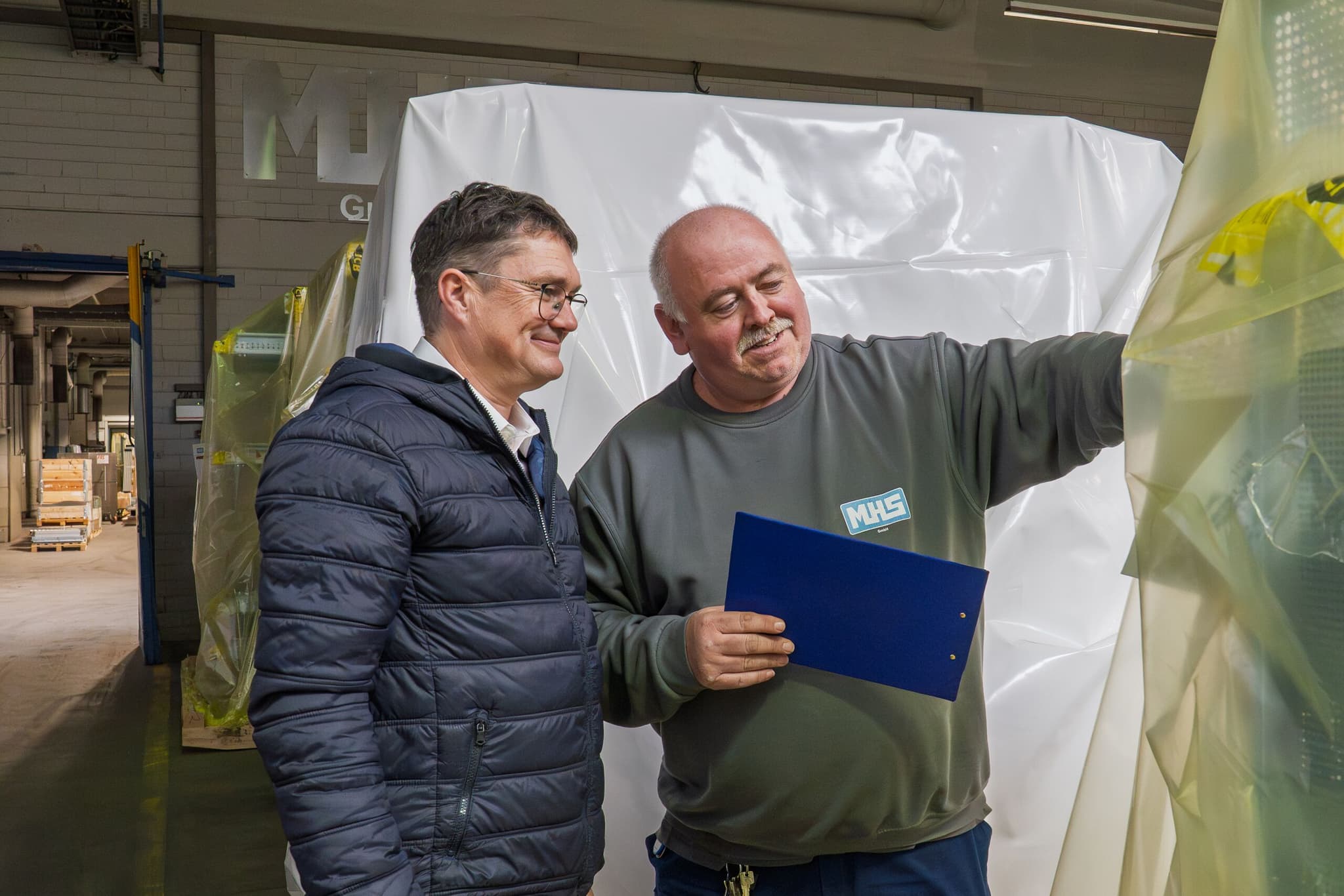 Zwei Mitarbeitende der MHS GmbH besprechen anhand einer Mappe die Verpackung einer Anlage