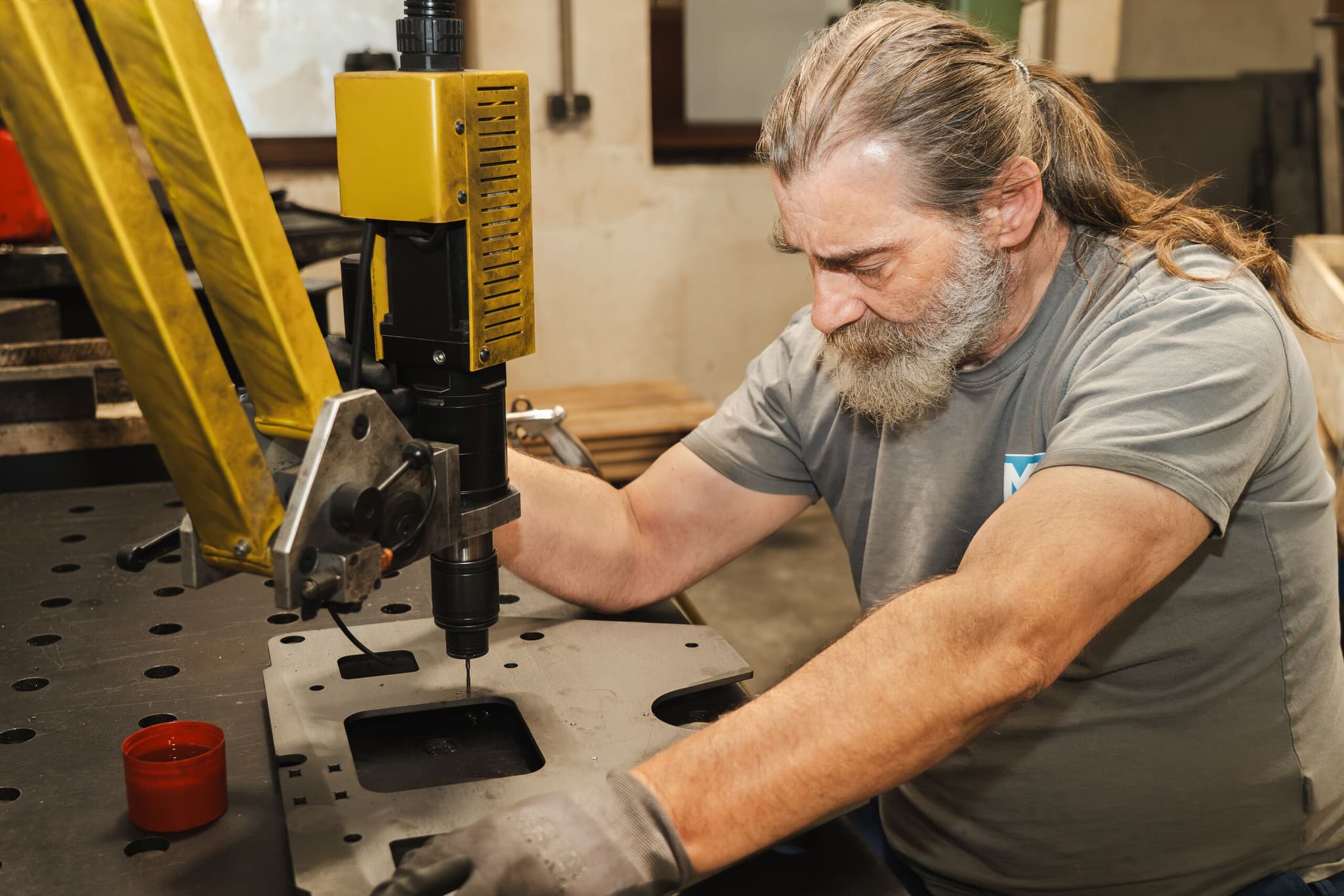 Mitarbeiter der MS Metalltechnik bohrt ein Blechteil an einer Ständerbohrmaschine